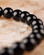 Pulsera de Turmalina Negra en curva descendente sobre superficie de madera