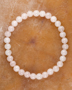 Pulsera de Cuarzo Rosa de 6 mm, pieza completa en círculo sobre superficie de piedra clara