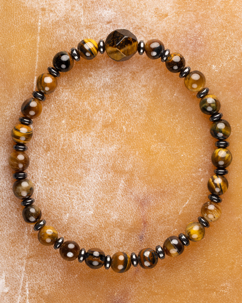 Pulsera de Ojo de Tigre y Hematita con icosaedro, pieza completa sobre superficie ambar
