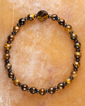 Pulsera de Ojo de Tigre y Hematita con icosaedro, pieza completa sobre superficie ambar