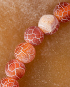 Detalle macro de cuentas de Cornalina Mate mostrando tonos naranja y crema