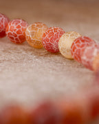Pulsera de Cornalina Mate en curva, cuentas nítidas al frente sobre superficie ocre