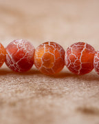 Detalle macro de cuentas de Cornalina Mate con tonos naranja, crema y rojizo