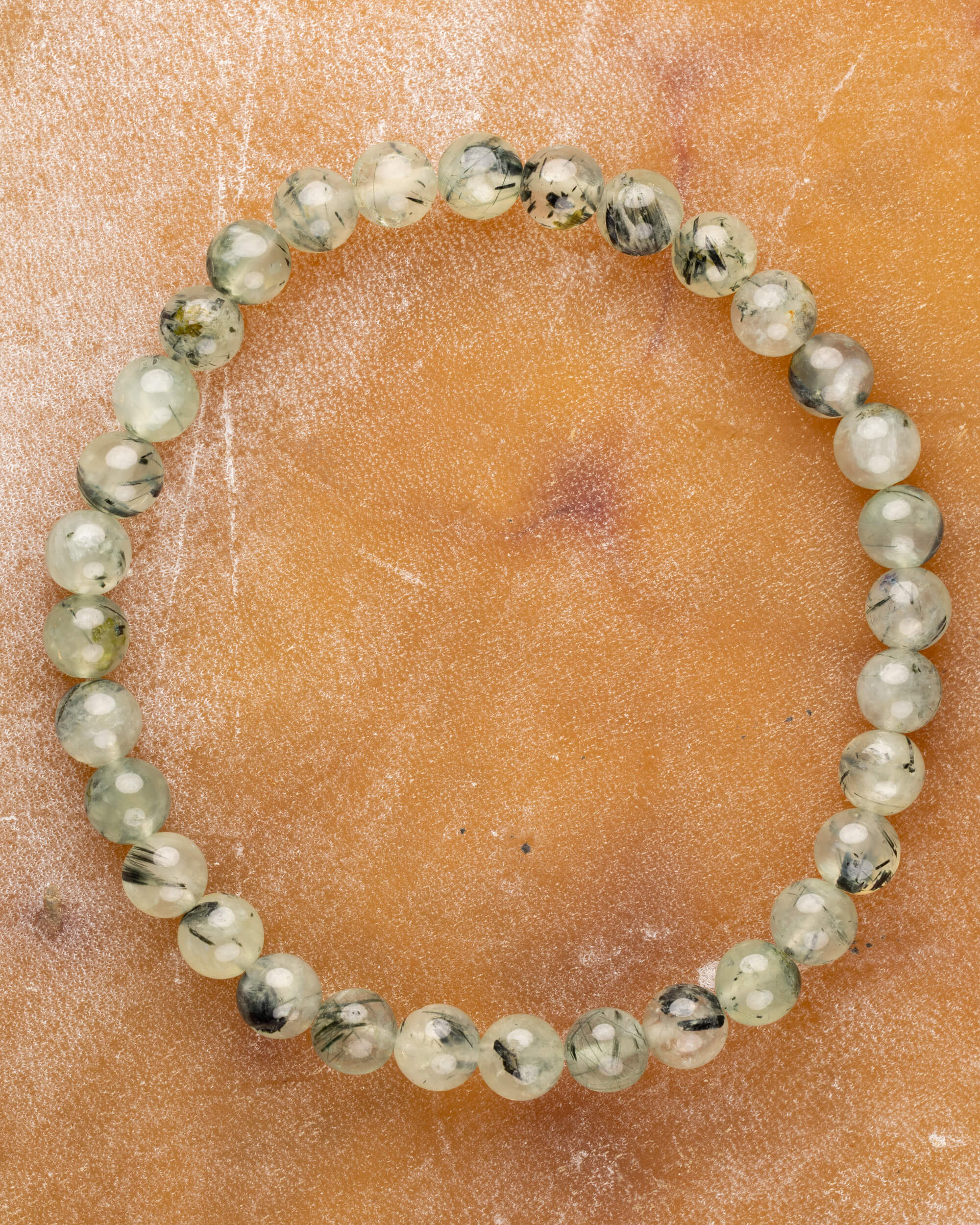 Pulsera de Prehnita de 6 mm, pieza completa en círculo sobre superficie color miel