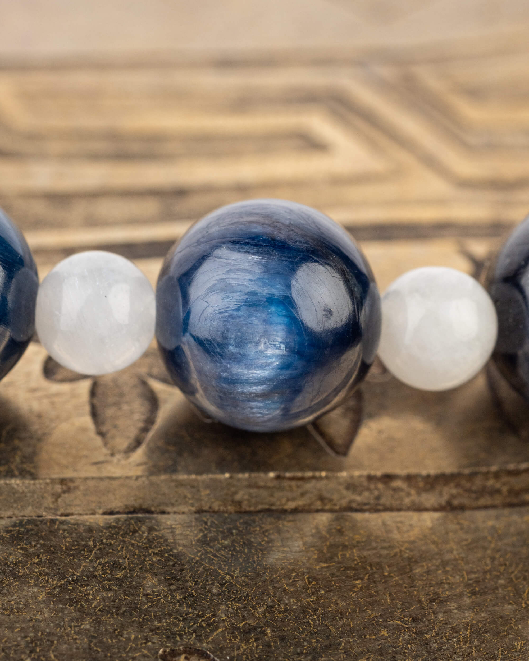 Detalle macro de la esfera azul profunda de Cianita entre cuentas blancas de Piedra Luna