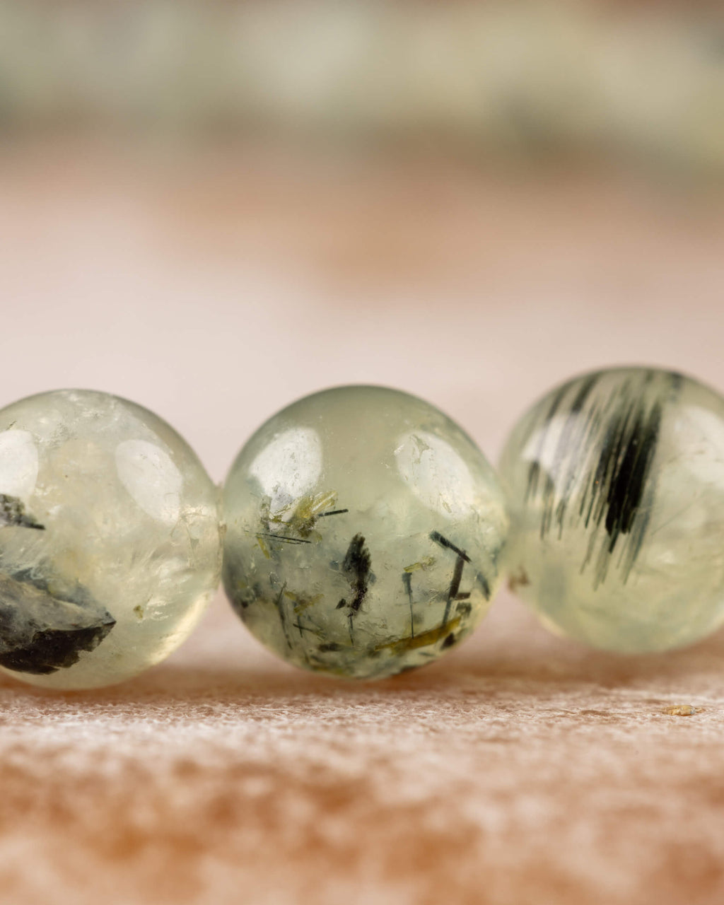Detalle macro de tres cuentas de Prehnita con reflejos e inclusiones oscuras