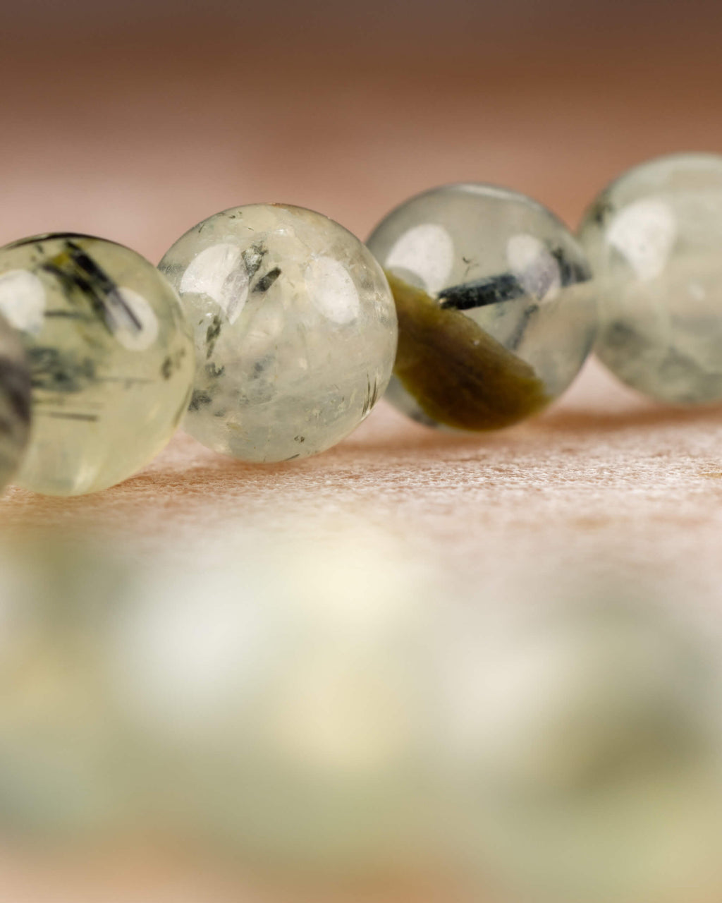 Detalle macro de cuentas de Prehnita con vetas verdosas y reflejos de luz
