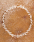 Pulsera de Cuarzo Transparente, pieza completa en círculo sobre superficie ambar