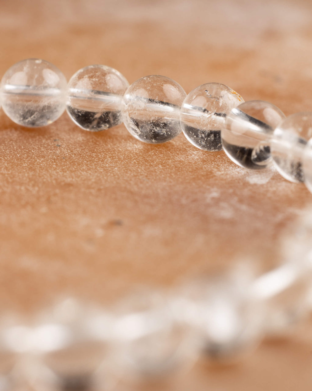Curva de la pulsera de Cuarzo Transparente en primer plano sobre superficie ambar