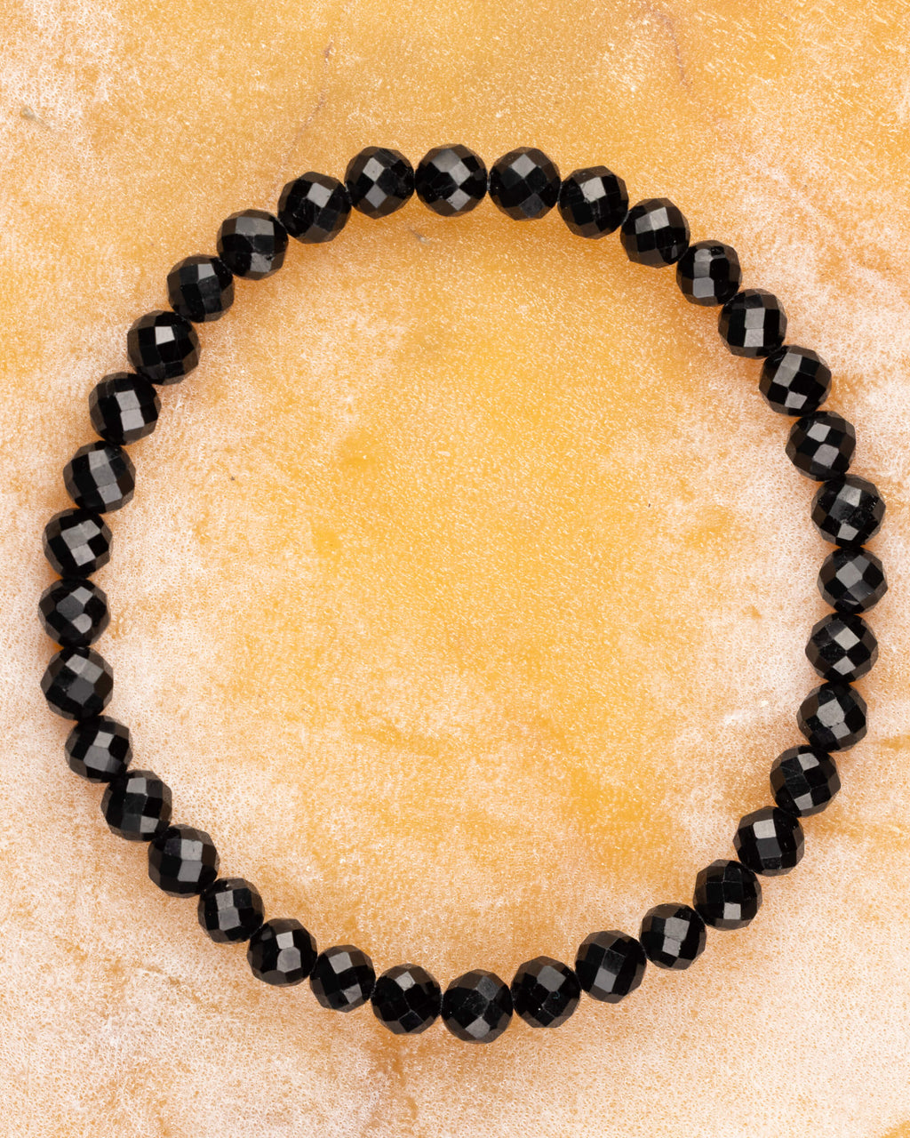 Pulsera de Turmalina Negra facetada de 6 mm, pieza completa sobre superficie dorada