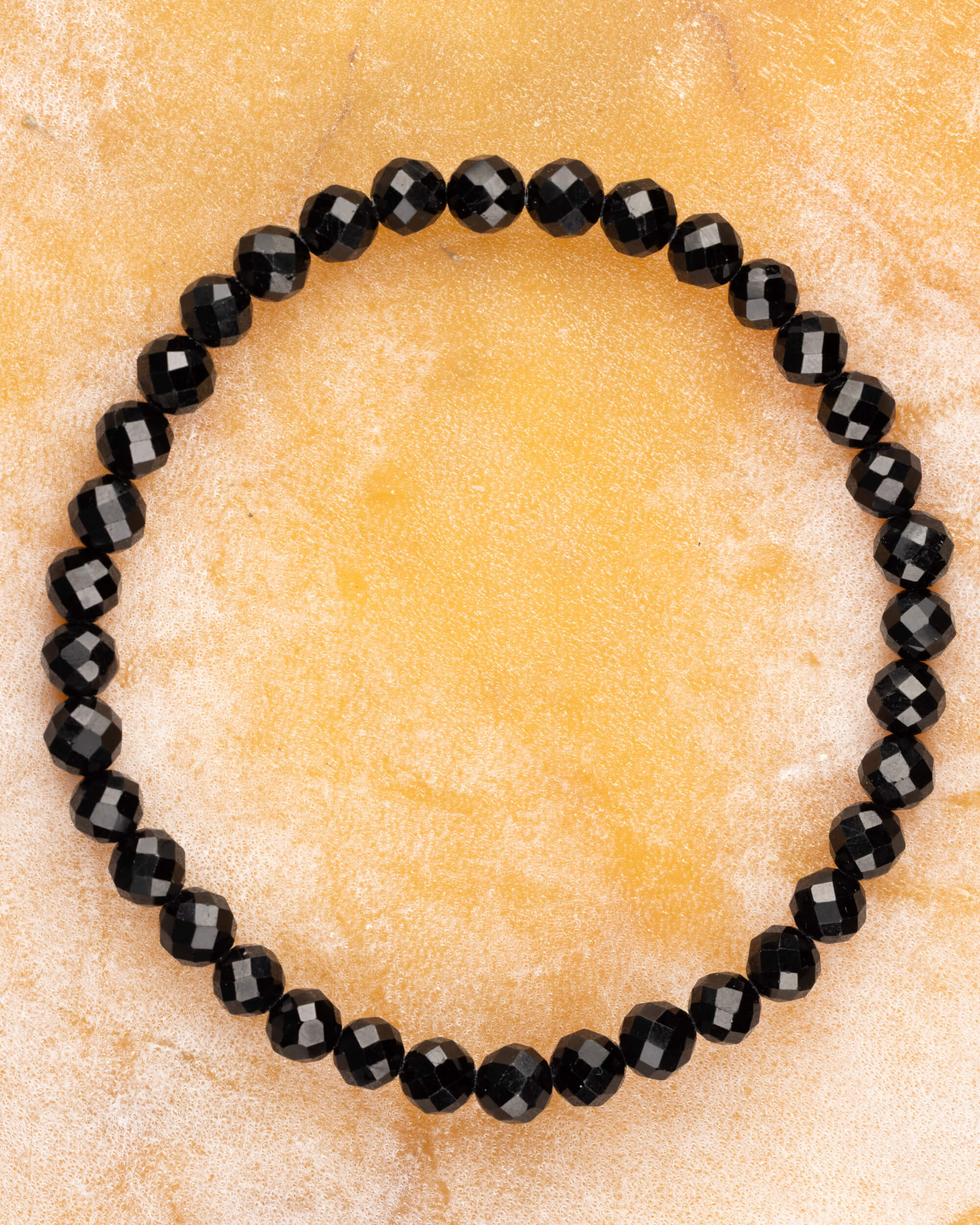 Pulsera de Turmalina Negra facetada de 6 mm, pieza completa sobre superficie dorada