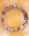 Pulsera de Charoita irregular, pieza completa en círculo sobre superficie color mostaza