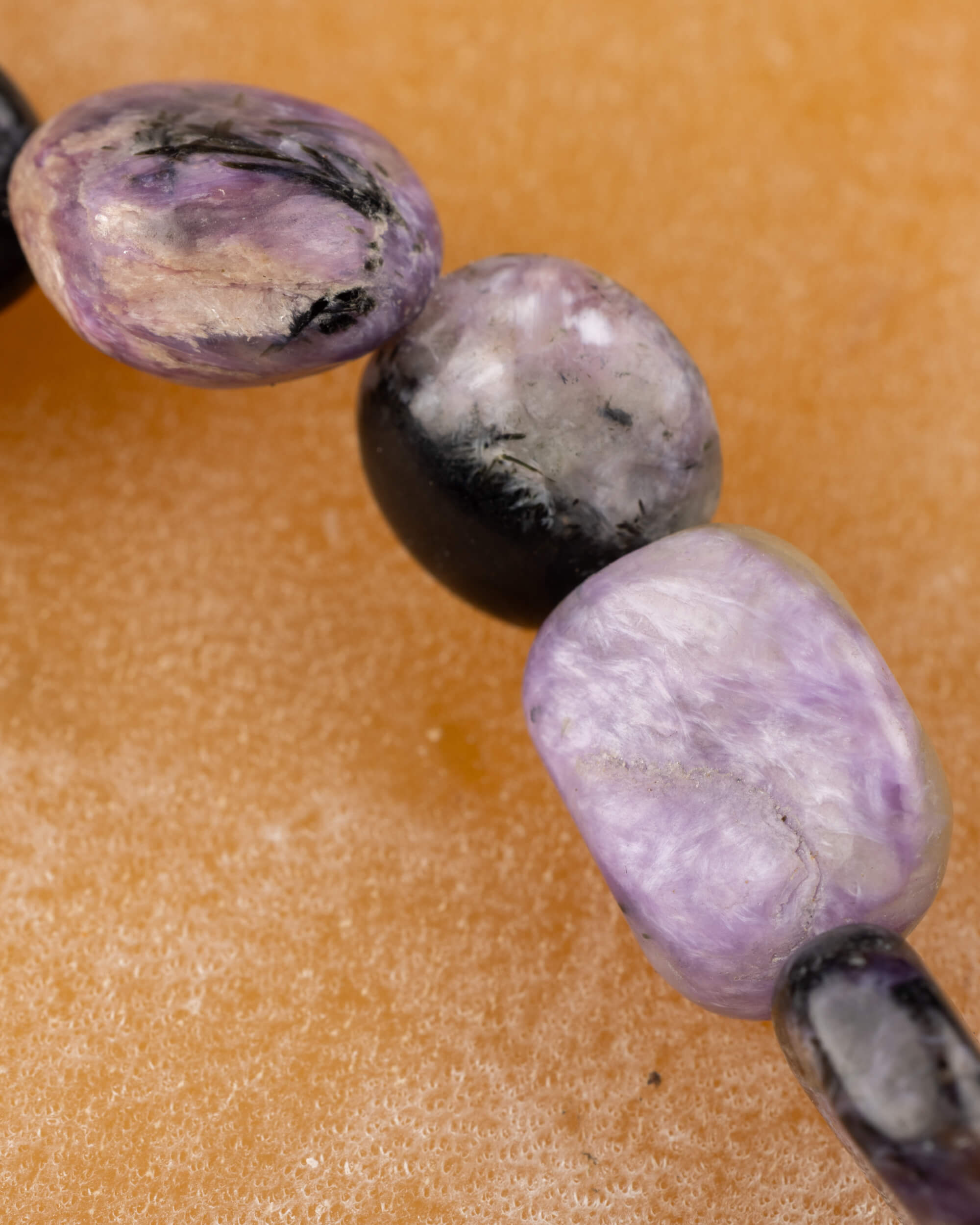 Detalle macro de piedras irregulares de Charoita en tonos morado y negro