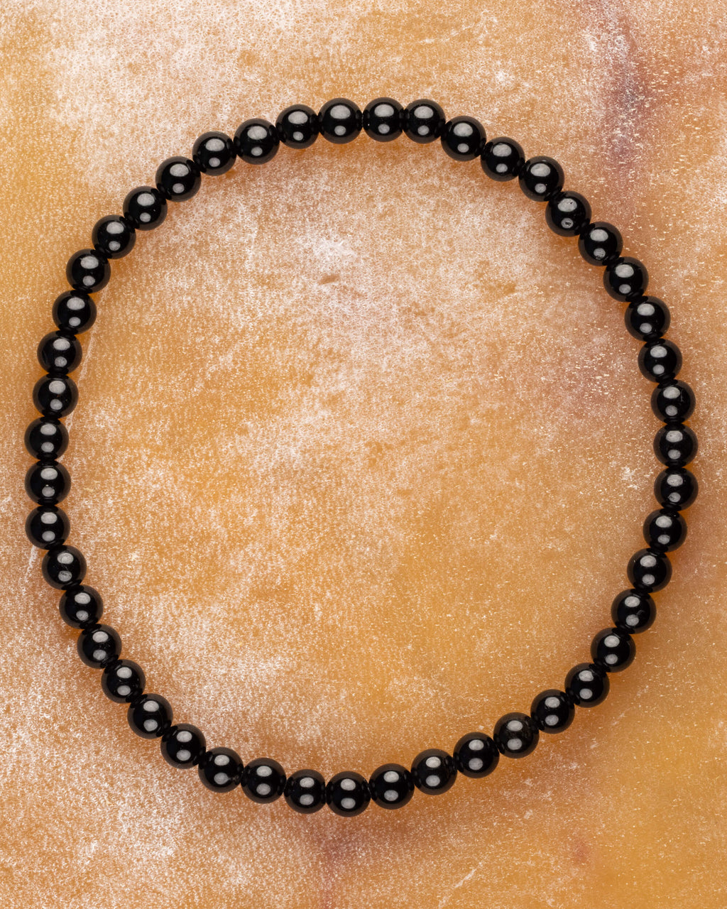 Pulsera de Turmalina Negra de 4 mm, pieza completa en círculo sobre piedra clara