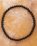 Pulsera de Turmalina Negra de 4 mm, pieza completa en círculo sobre piedra clara