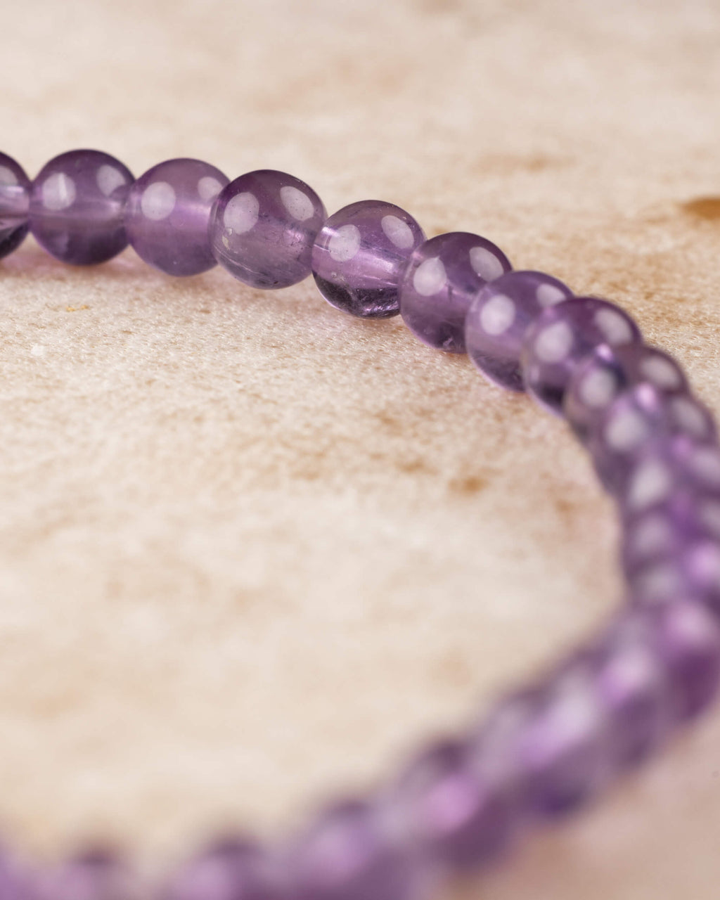 Pulsera de Amatista de 4 mm en ángulo, cuentas en curva sobre superficie clara