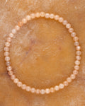 Pulsera de Piedra Sol Naranja de 4 mm, pieza completa en círculo sobre superficie dorada