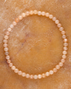 Pulsera de Piedra Sol Naranja de 4 mm, pieza completa en círculo sobre superficie dorada