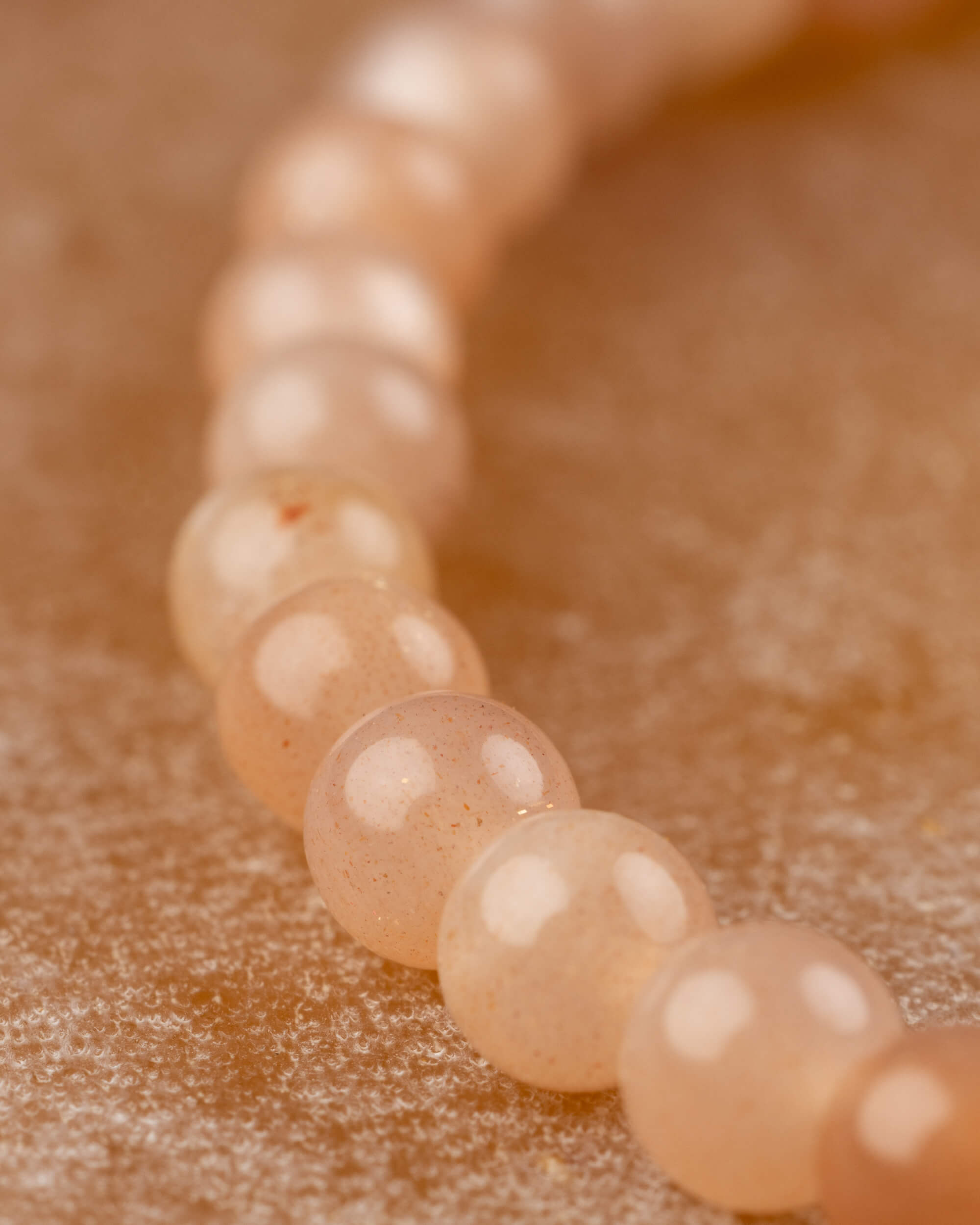 Detalle macro de las cuentas de Piedra Sol Naranja con destellos dorados