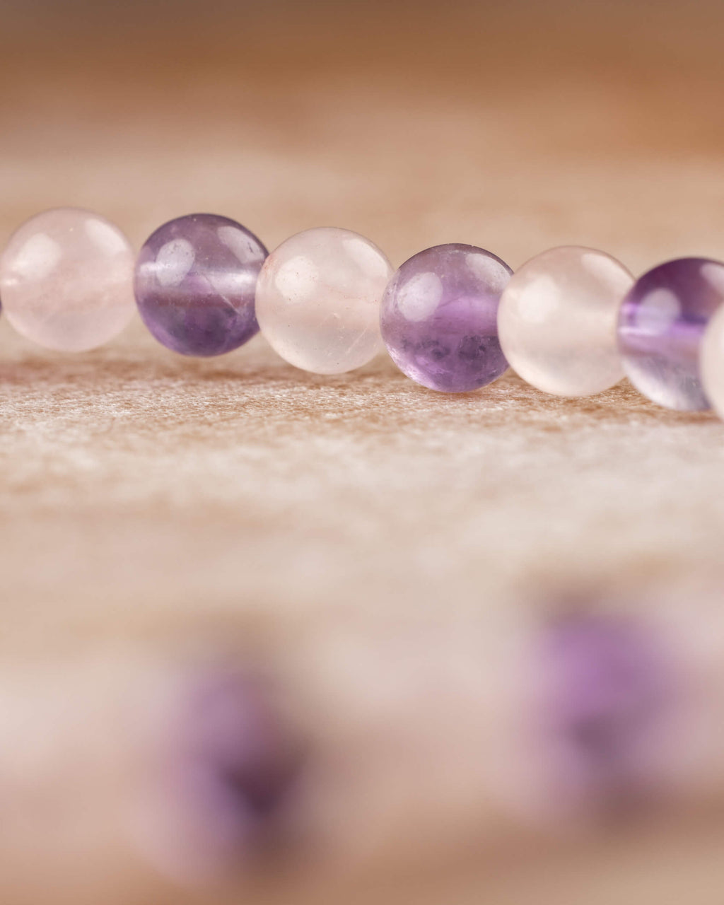 Pulsera de Amatista y Cuarzo Rosa vista de perfil, cuentas alternadas en fila sobre madera
