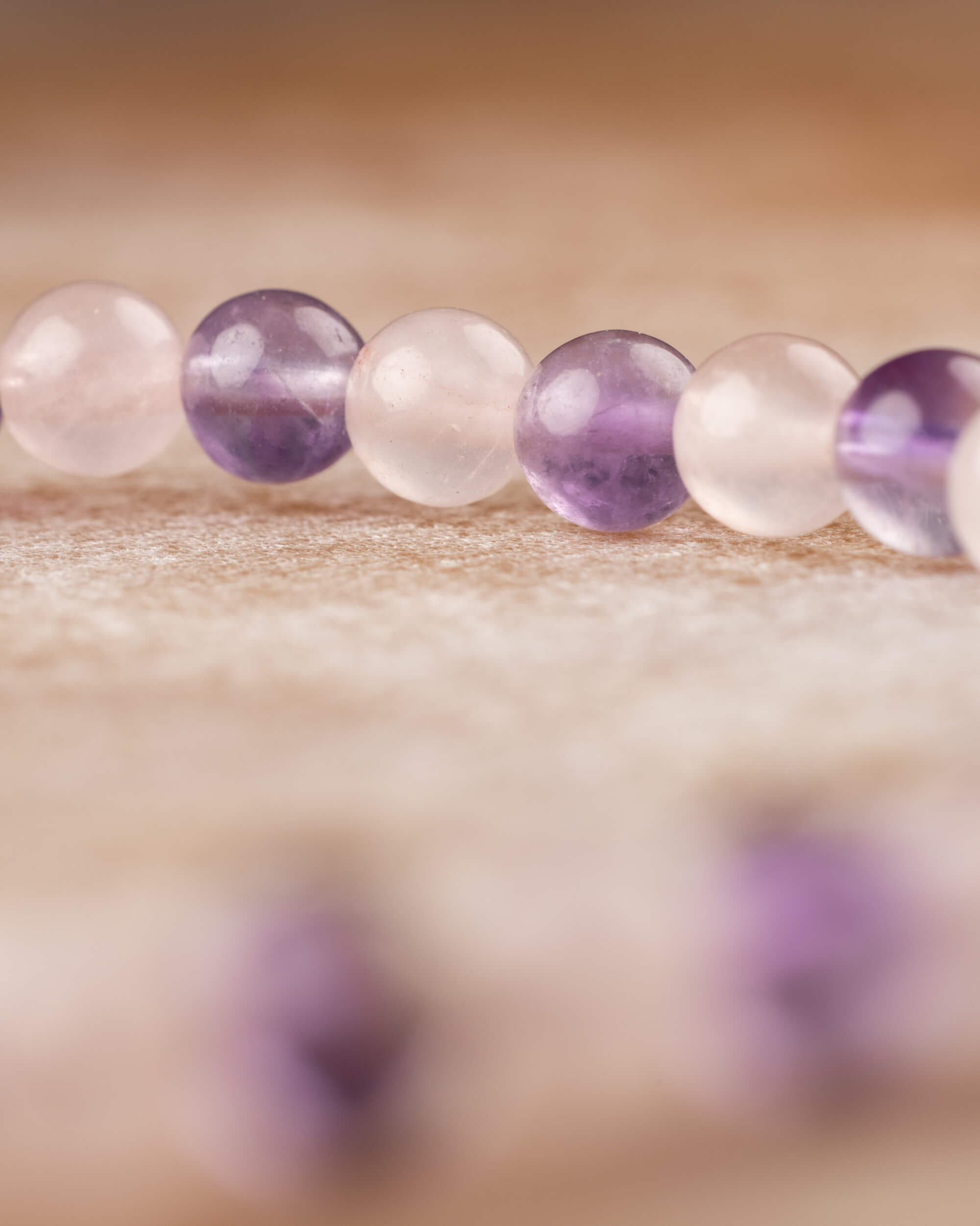 Pulsera de Amatista y Cuarzo Rosa vista de perfil, cuentas alternadas en fila sobre madera