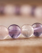 Detalle macro de cuentas de Amatista y Cuarzo Rosa con fondo de la misma pulsera desenfocado