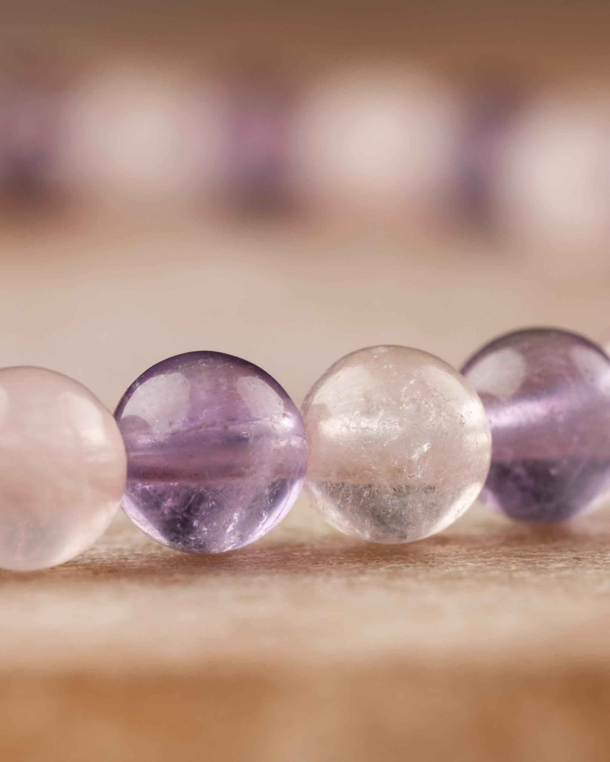 Detalle macro de cuentas de Amatista y Cuarzo Rosa con fondo de la misma pulsera desenfocado
