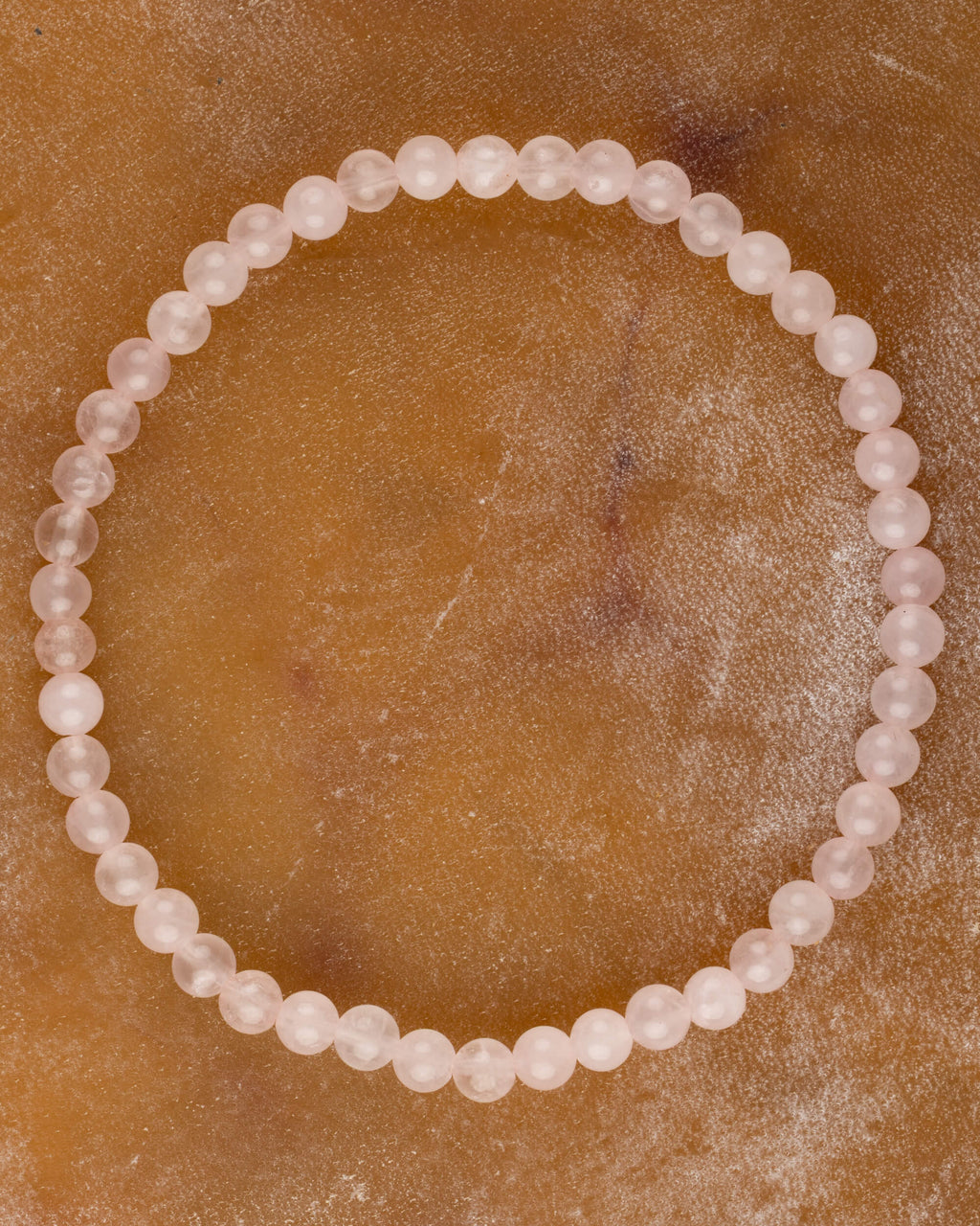 Pulsera de Cuarzo Rosa de 4 mm, pieza completa en círculo sobre superficie marmoleada