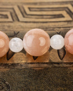 Detalle macro de una esfera de Piedra Sol entre cuentas blancas de Piedra Luna