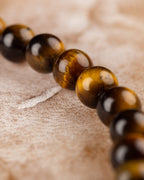 Pulsera de Ojo de Tigre en ángulo diagonal sobre superficie de tela clara
