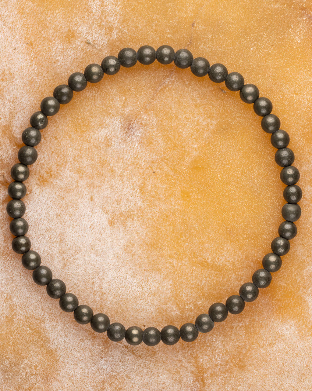 Pulsera de Pirita de 4 mm, pieza completa en círculo sobre superficie color miel