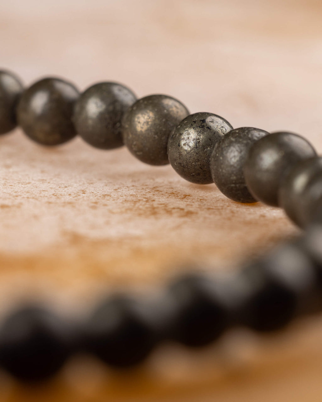 Pulsera de Pirita en perspectiva, cuentas metálicas frente a un segundo tramo desenfocado