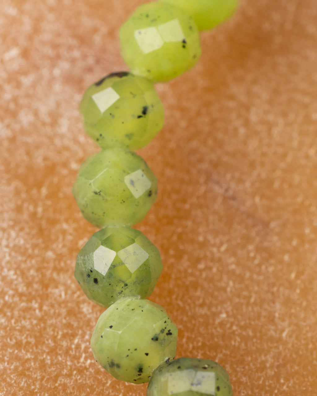 Detalle macro extremo de las cuentas facetadas de Jade Verde en fila vertical