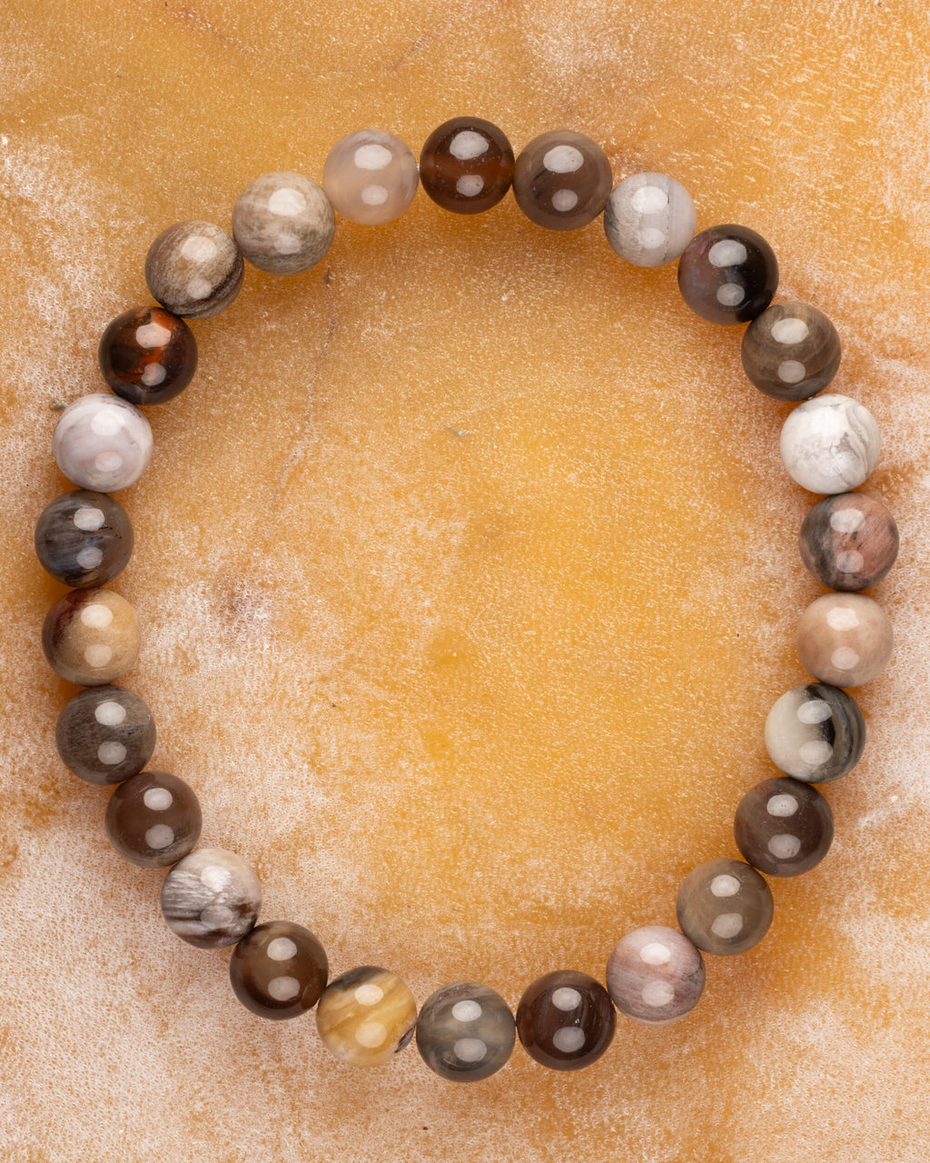 Pulsera de Madera Petrificada de 8 mm, pieza completa sobre superficie ocre