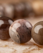 Detalle macro de una cuenta rosada veteada de Madera Petrificada