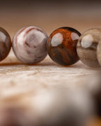 Detalle macro de cuentas cafés, blancas y anaranjadas de Madera Petrificada