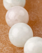 Primer plano de cuentas de Berilos lisas en tonos blanco y rosa palido
