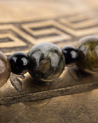 Detalle macro de una cuenta de Turmalina Verde junto a esfera negra del codificador