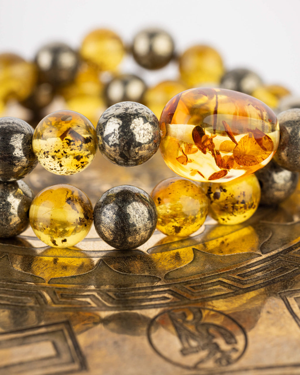 Detalle macro de cuentas de Ámbar y Pirita con reflejo dorado sobre disco grabado