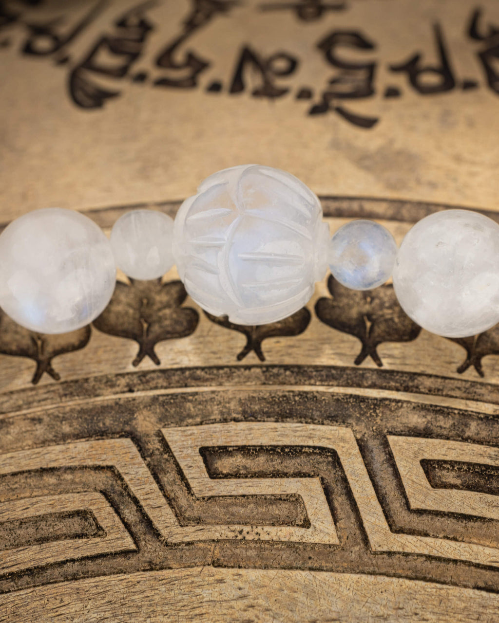 Detalle macro de la cuenta tallada de Piedra Luna entre cuentas redondas del codificador