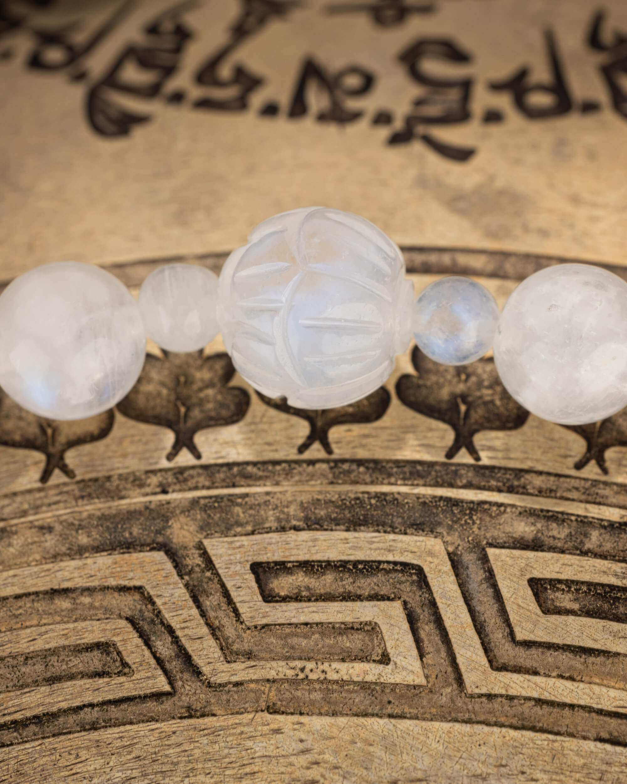 Detalle macro de la cuenta tallada de Piedra Luna entre cuentas redondas del codificador