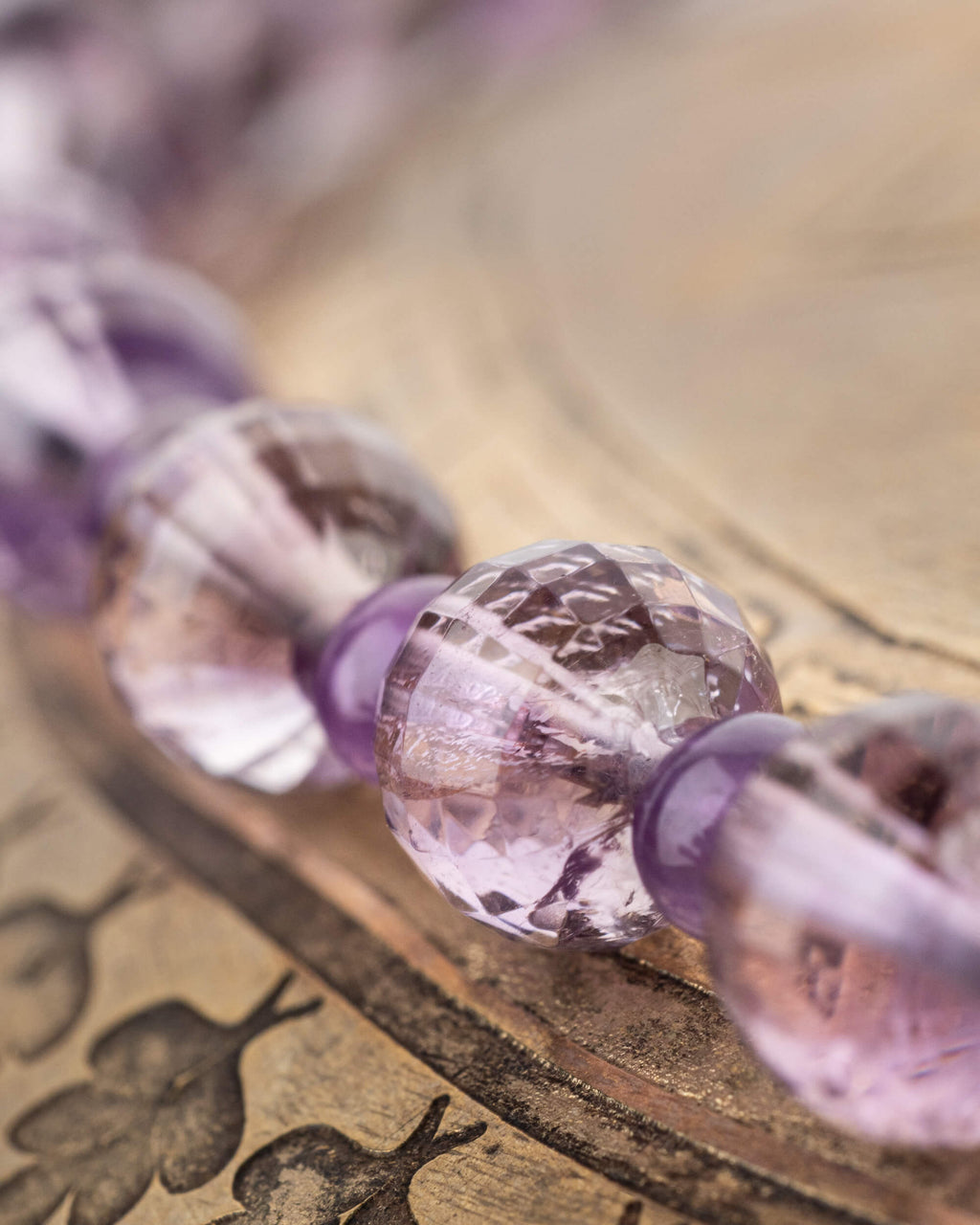 Detalle macro de las cuentas facetadas de Amatista con vetas violeta y transparentes