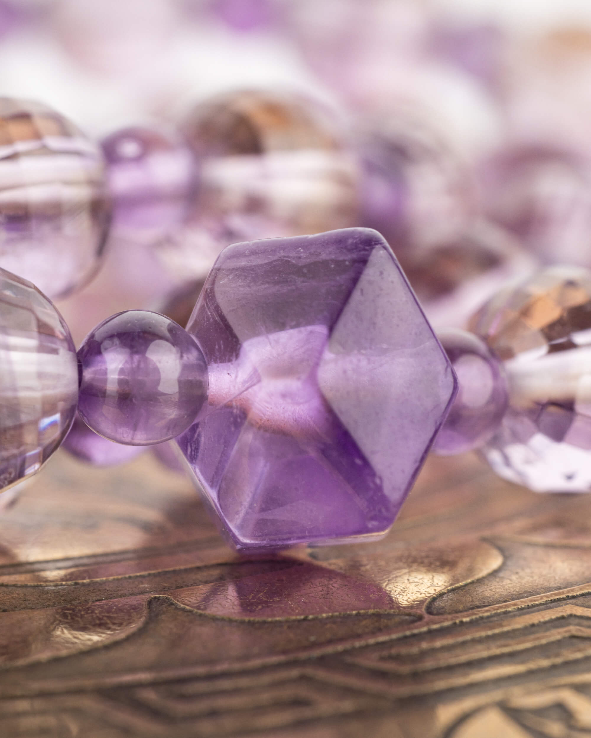 Detalle macro de la cuenta hexagonal de Amatista rodeada de cuentas facetadas