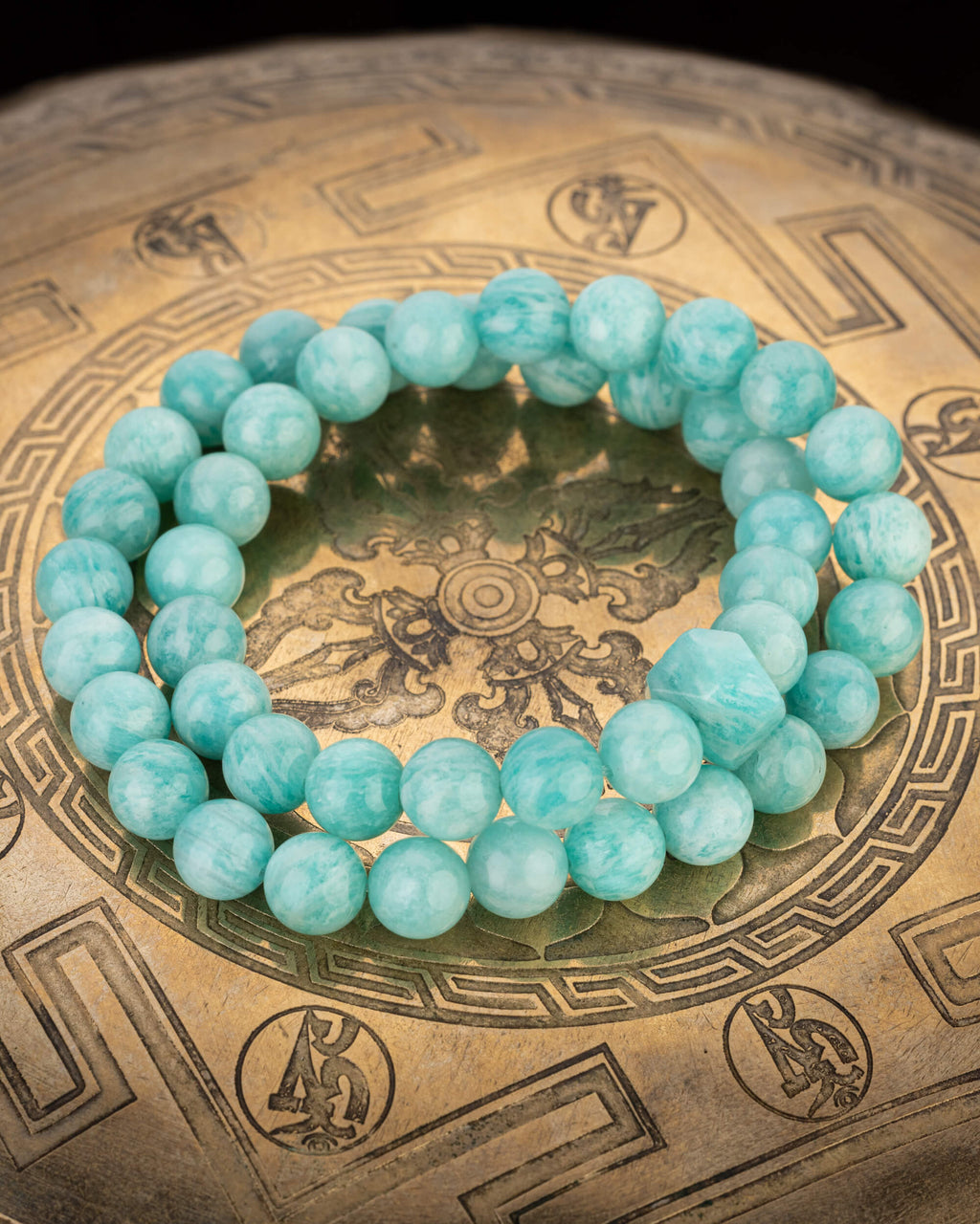 Codificador de Amazonita Aqua completo, en forma circular sobre un cuenco tibetano de bronce