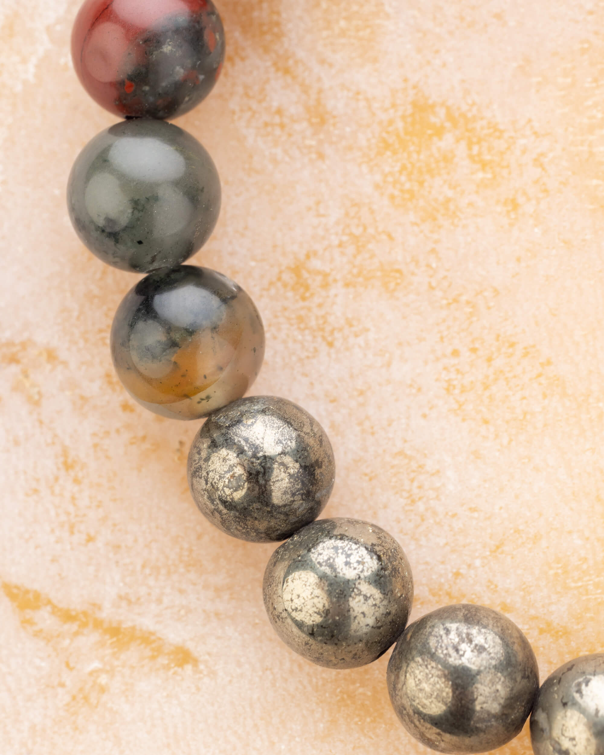 Vista en perspectiva de las cuentas de Rubí, Piedra Sangre y Pirita de la pulsera Capricornio