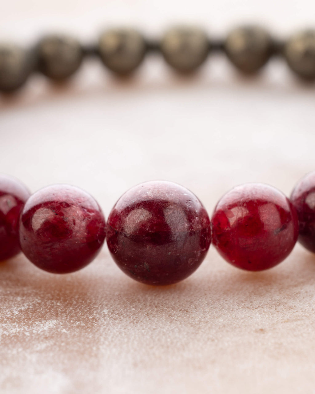 Detalle macro de las cuentas de Rubí y Pirita de la pulsera Capricornio