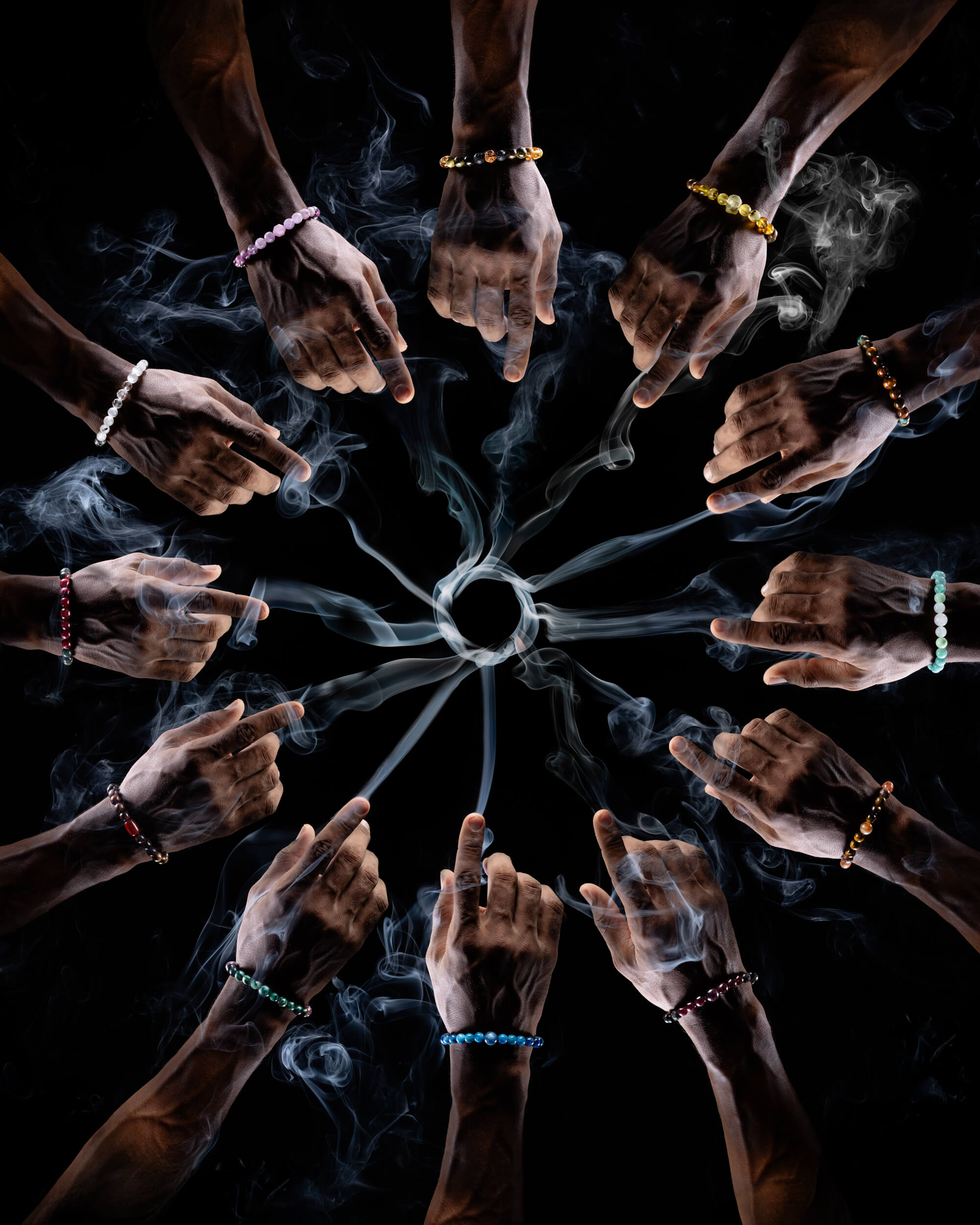 Doce manos con humo de copal, cada una con una pulsera zodiacal distinta puesta