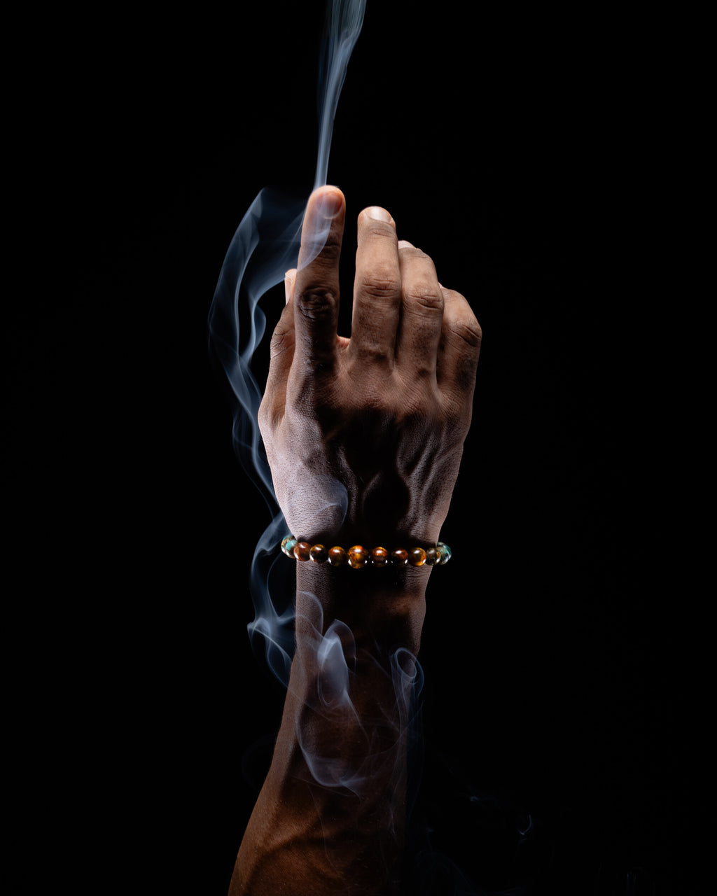 Pulsera Zodiacal Géminis puesta en la muñeca, entre volutas de humo