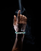Pulsera Zodiacal Cáncer puesta en la muñeca, entre volutas de humo