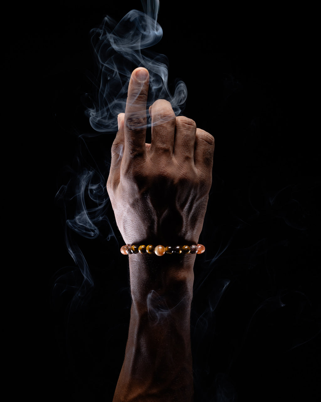 Pulsera zodiacal Leo puesta en la muñeca, con humo de copal alrededor